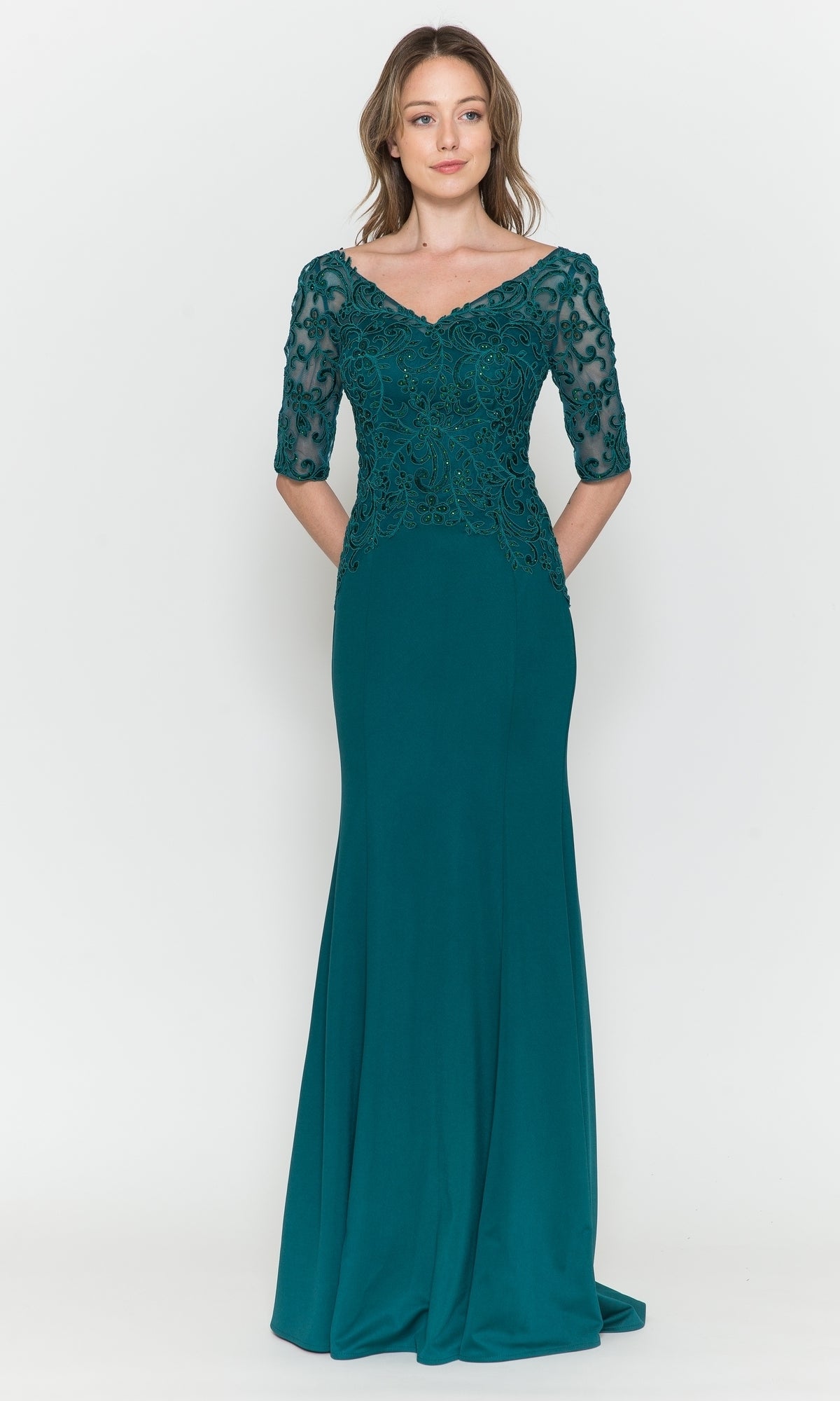 A woman in the Embroidered Sheer-Sleeved Formal Prom Dress 8560 in emerald, with sheer lace half sleeves and an embroidered bodice, stands against a plain white background.